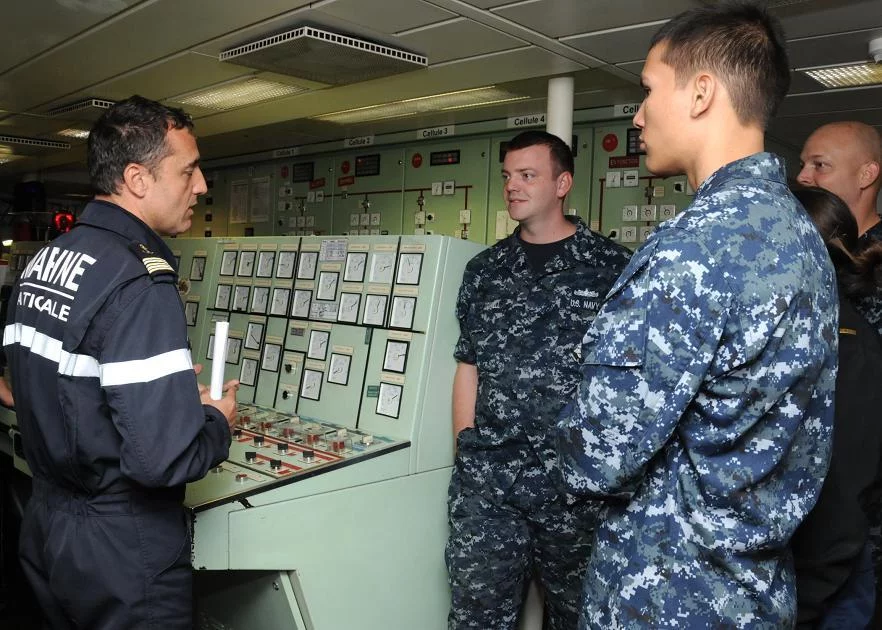 Le capitaine de frégate Renaud Bondil, commandant du Prairial, présente la salle des machines à des marins du croiseur USS Chosin