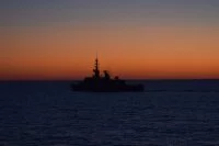 La frégate Aconit à contre-jour sur le soleil couchant