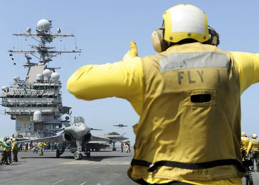 Un directeur de pont d'envol américain dirige un Rafale français vers la catapulte du Theodore Roosevelt
