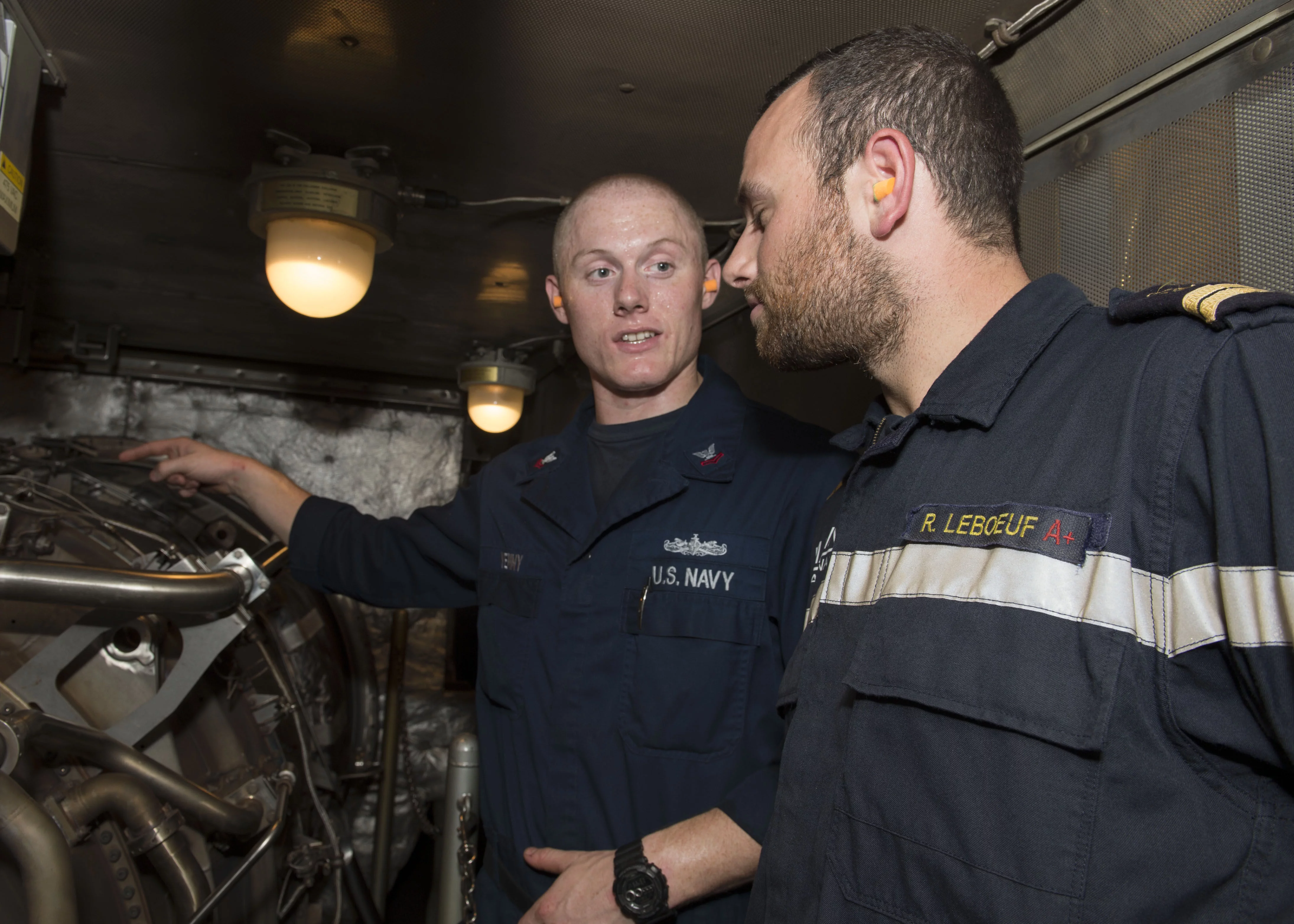 Le mécanicien Adam Yenny, du destroyer USS Bulkeley, fait visiter au second-maître Renaud Leboeuf, de la frégate Aconit, les parties techniques du destroyer