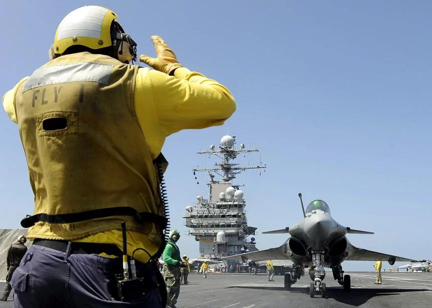 Un directeur de pont d'envol américain dirige un Rafale français vers la catapulte du Theodore Roosevelt